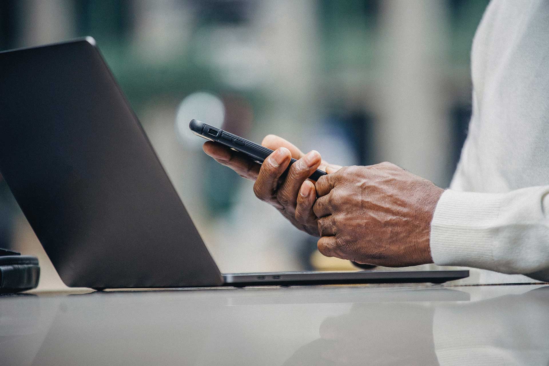 man with phone and laptop at table